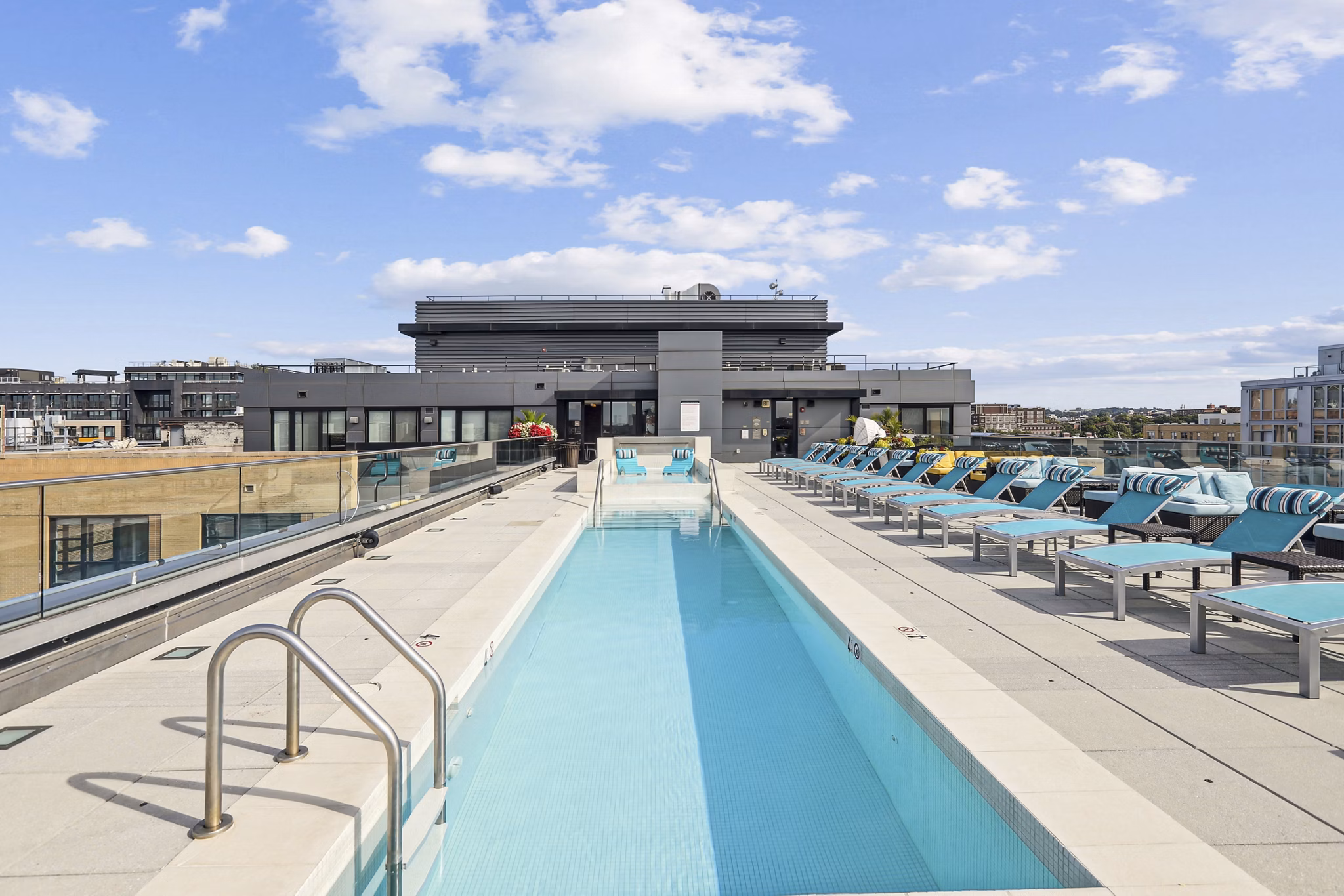 Luxurious pool at The Louis Apartments with comfortable lounge chairs and greenery, offering a serene escape for residents