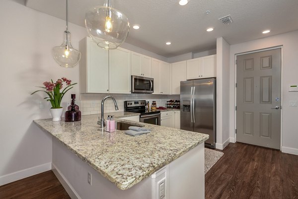 Modern kitchen featuring stainless steel appliances and granite countertops at Urbana Apartments
