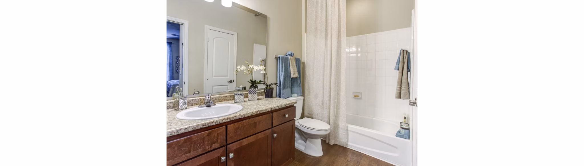 Modern bathroom with dual sinks and tiled shower at Town Center at Lakeside Village Apartments