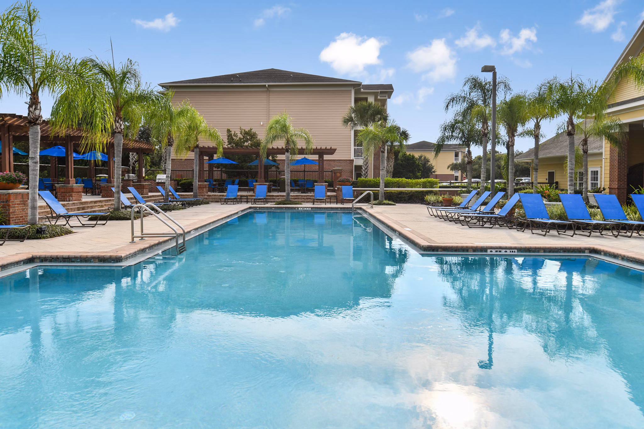 Resort-style pool at Town Center at Lakeside Village Apartments with surrounding lounge chairs and lush landscaping
