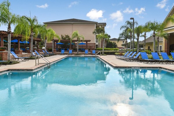 Resort-style pool at Town Center at Lakeside Village Apartments with surrounding lounge chairs and lush landscaping