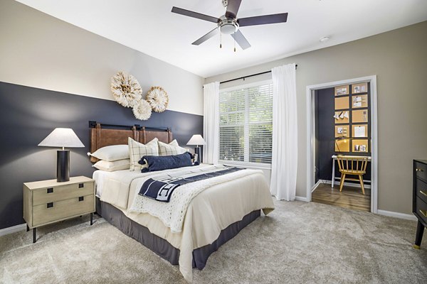 Cozy bedroom with modern decor at Tradition at Stonewater Apartments, featuring a plush bed and ample natural lighting