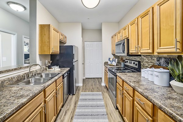 Modern kitchen with granite countertops and stainless steel appliances at Tradition at Stonewater Apartments