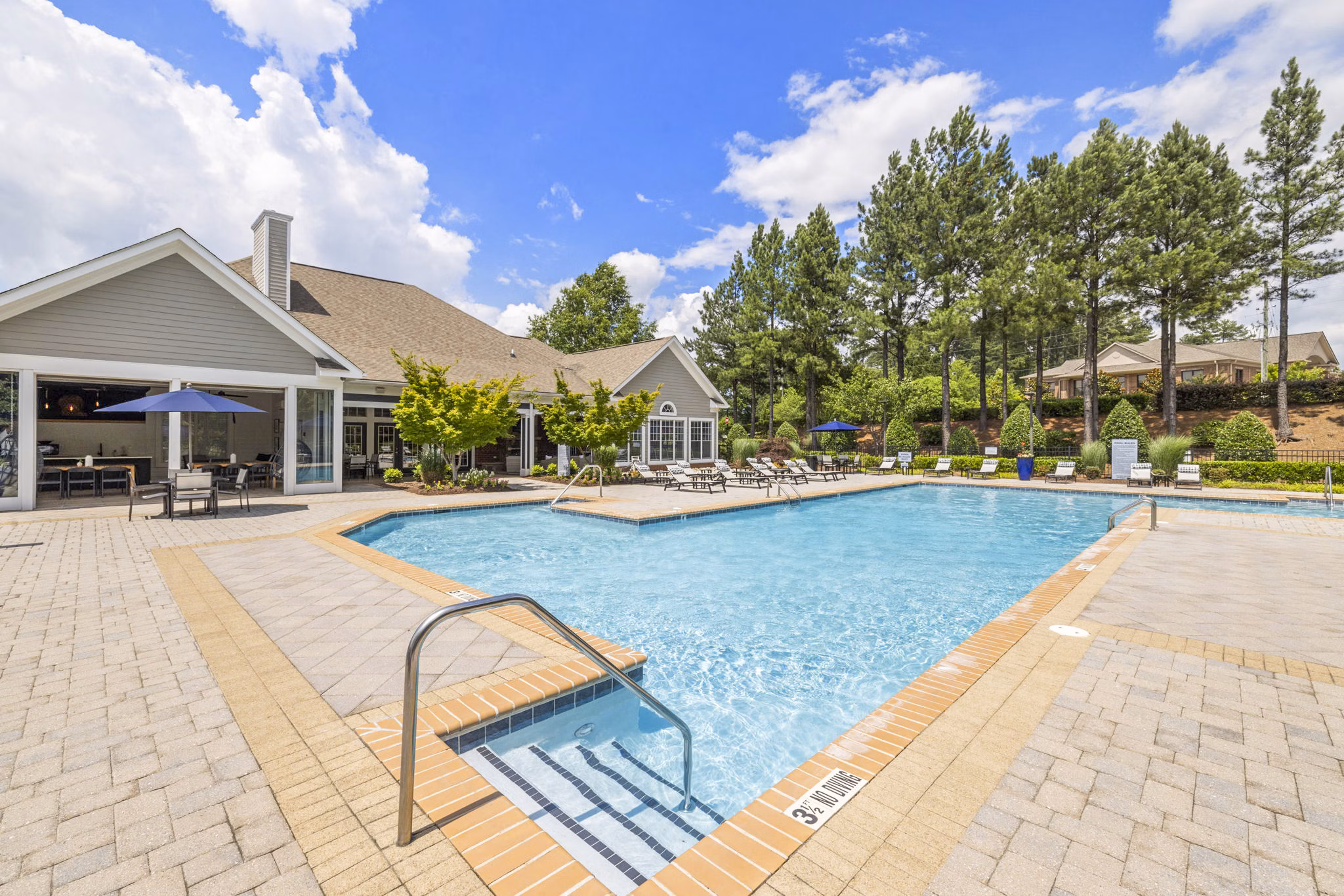 Poolside oasis at Tradition at Stonewater Apartments featuring surrounded by lush landscaping and relaxing lounge areas