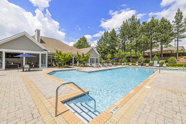 Poolside oasis at Tradition at Stonewater Apartments featuring surrounded by lush landscaping and relaxing lounge areas