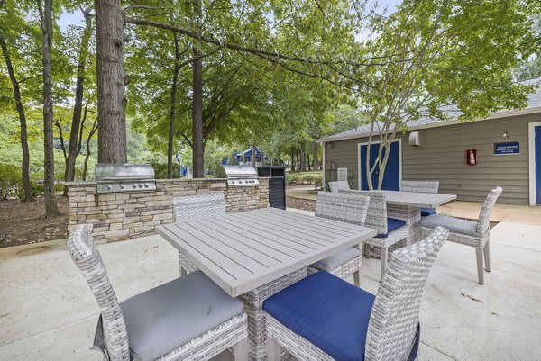 Grill area with modern seating and lush landscaping at Sailboat Bay Apartments