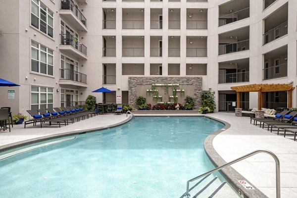 Resort-style pool at Mosaic South End Apartments with lounge areas and palm trees