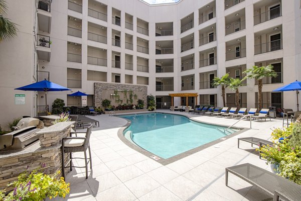 Modern outdoor pool area at Mosaic South End Apartments with lounge seating and city skyline views