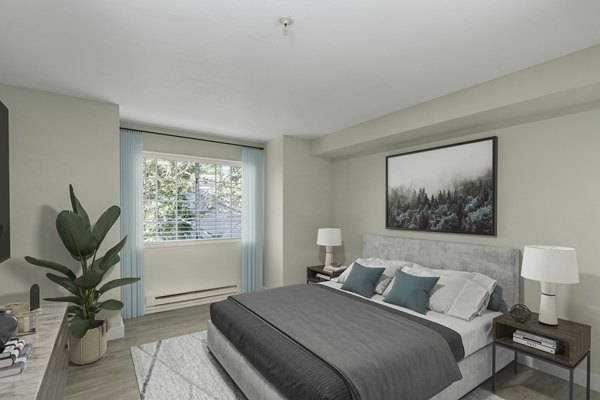 Cozy bedroom with modern decor at BluWater Apartments, featuring plush bedding and ample natural light