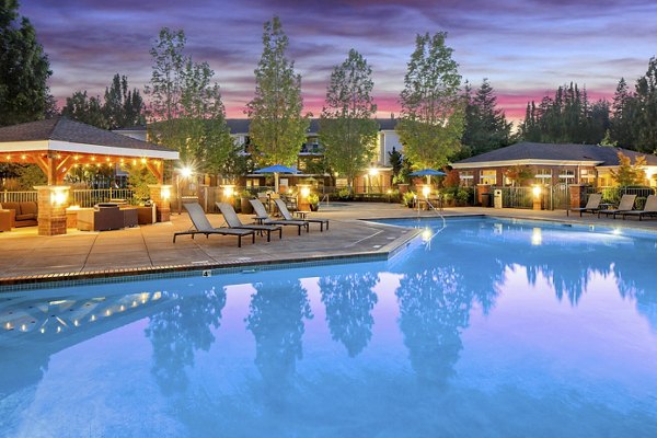 Outdoor pool with lounge chairs at Arya at Hedges Creek Apartments, luxury living in a serene setting