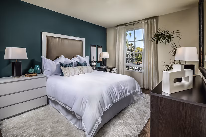 Cozy bedroom with modern decor at Trio Apartments, featuring sleek furnishings and soft lighting perfect for relaxation and comfort