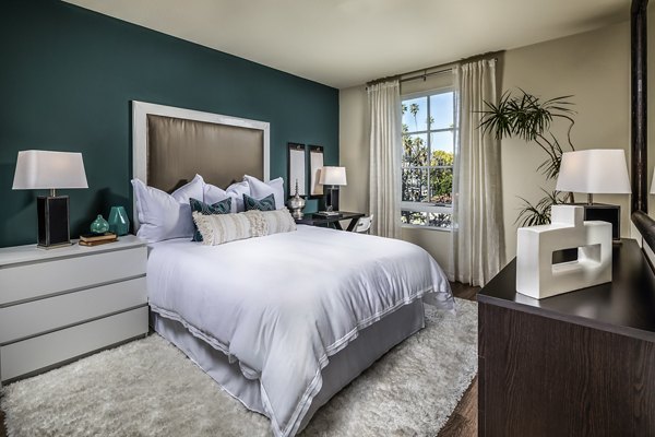 Cozy bedroom with modern decor at Trio Apartments, featuring sleek furnishings and soft lighting perfect for relaxation and comfort