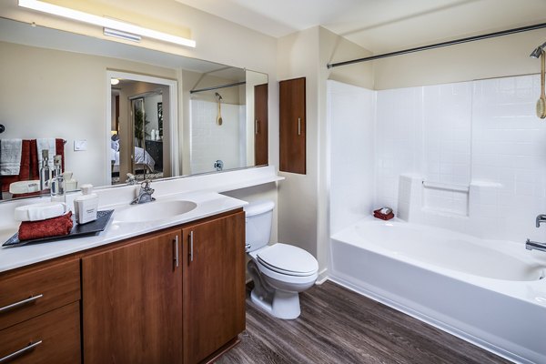 Modern bathroom featuring marble countertops and glass shower in Trio Apartments