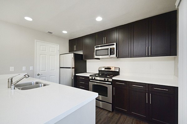 Modern kitchen with stainless steel appliances and granite countertops in Westcreek Apartments
