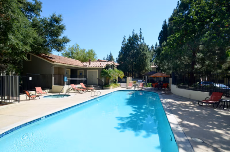 Resort-style pool surrounded by lush landscaping at Westcreek Apartments