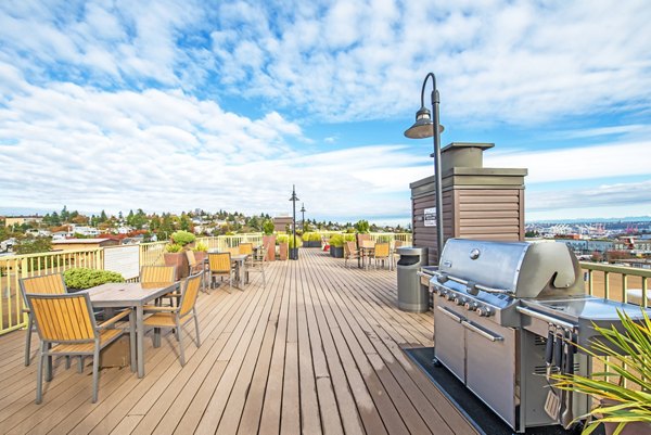 Modern grill area at Link Apartments featuring stainless steel BBQ stations and outdoor seating