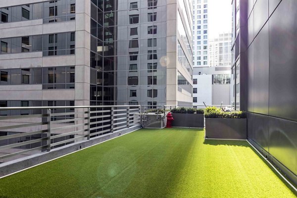 Dog-friendly fenced park at Aspira Apartments with agility structures and seating areas
