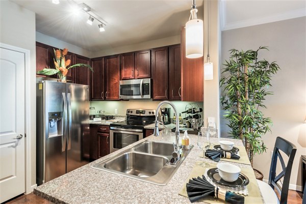 Kitchen featuring modern appliances and island seating in Deseo at Grand Mission Apartments