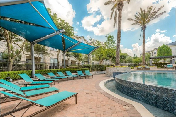 Outdoor pool surrounded by lush landscaping at Deseo at Grand Mission Apartments, offering luxury living and relaxation amenities