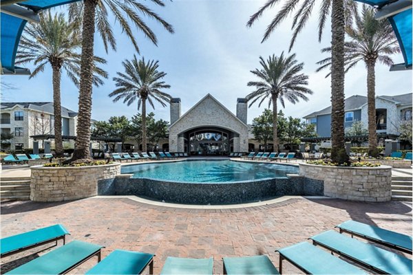 Sparkling pool surrounded by lush landscaping at Deseo at Grand Mission Apartments