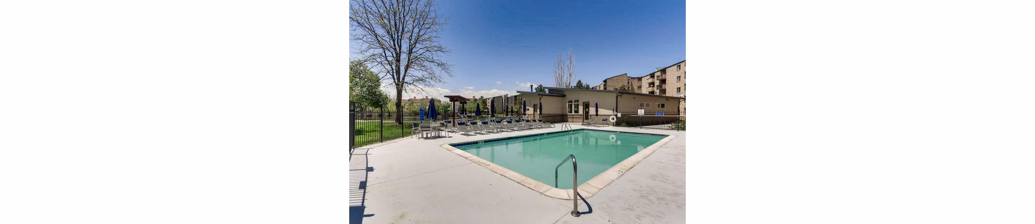 Resort-style pool at Lakeview Towers at Belmar Apartments with shaded lounge chairs and landscaped surroundings