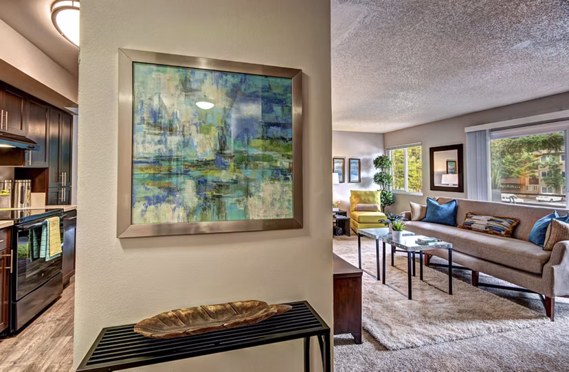 Elegant living room with plush seating and a large window at Central Park East Apartments