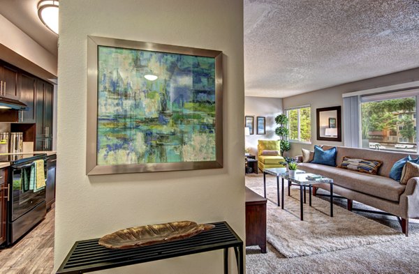 Elegant living room with plush seating and a large window at Central Park East Apartments