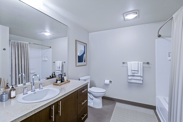 Modern bathroom with sleek fixtures and large mirror in Allez Apartments
