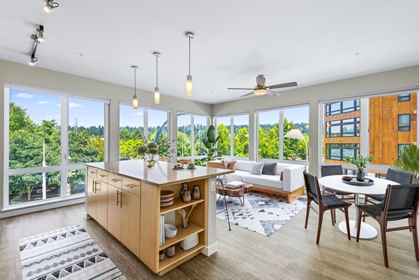 Spacious living room with modern decor at Allez Apartments, featuring large windows and sleek furnishings