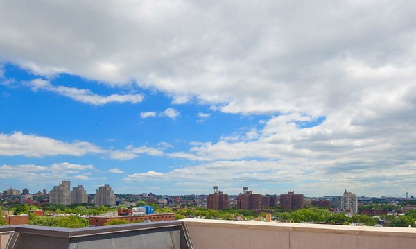 Cityscape featuring luxury apartments, lush trees, and a partly cloudy sky