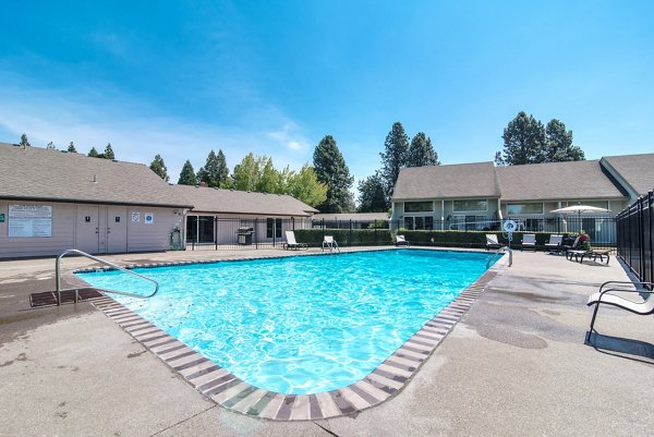 Relaxing pool area with lounge chairs and lush landscaping at Meadowlawn Apartments