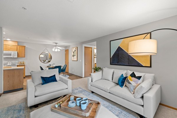 Spacious living room with modern furnishings in Highland Hills Apartments, featuring large windows and stylish decor