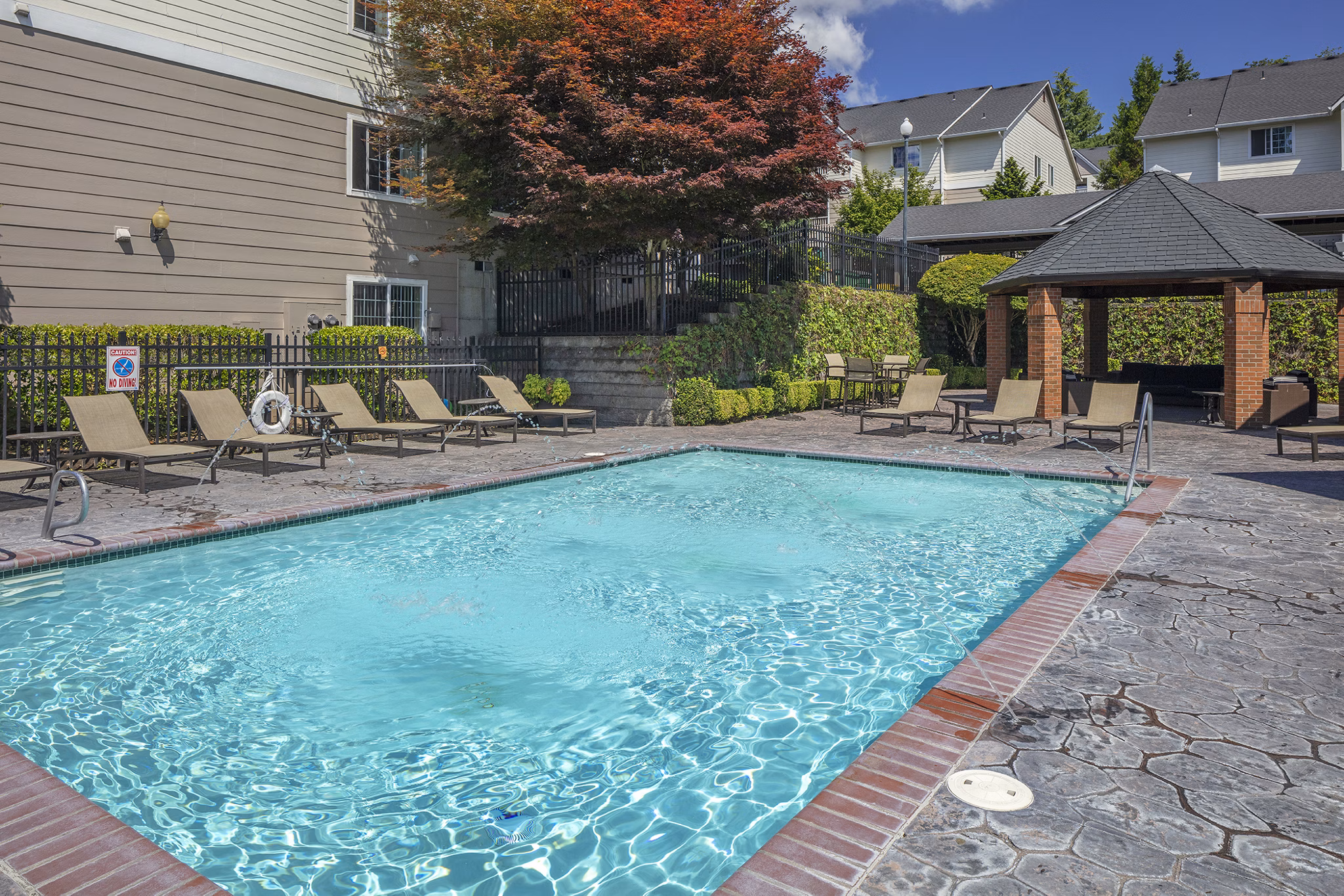 Resort-style pool at Highland Hills Apartments with lounge chairs and landscaping