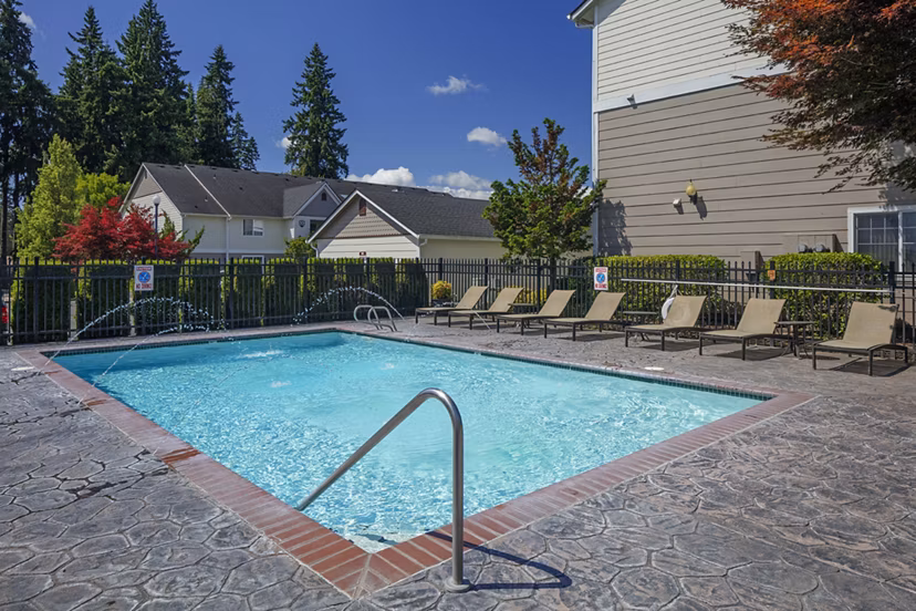 Aerial view of the resort-style pool at Highland Hills Apartments with surrounding lounge chairs and lush landscaping