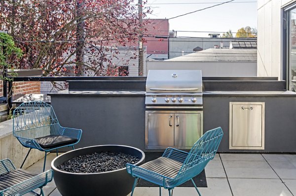 Grill area with modern seating and BBQ at The Addy Apartments