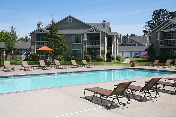 Poolside lounge area at Jackson School Village Apartments with umbrellas and seating for residents to enjoy leisure time