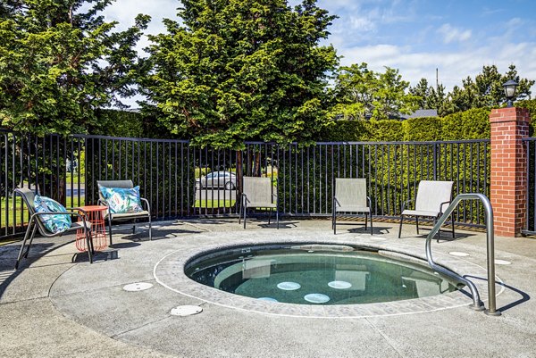 Relaxing outdoor hot tub at Village at Cascade Park Apartments, perfect for unwinding in a serene community setting