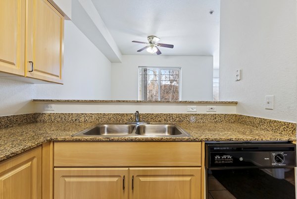 Contemporary kitchen with granite countertops and stainless steel appliances in Logger Creek at Parkcenter Apartments
