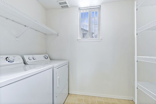 Laundry room featuring modern washers and dryers at Logger Creek at Parkcenter Apartments