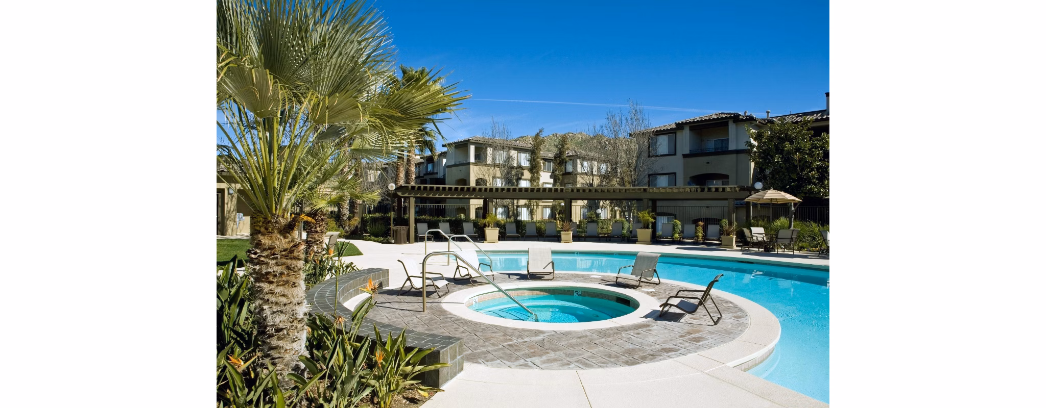 Serene outdoor pool area at Castlerock Apartments with lounge chairs and lush landscaping