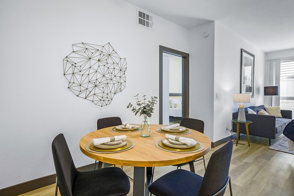 Dining room featuring elegant chandelier and modern furnishings at Enclave Apartments, luxurious living option in vibrant urban setting