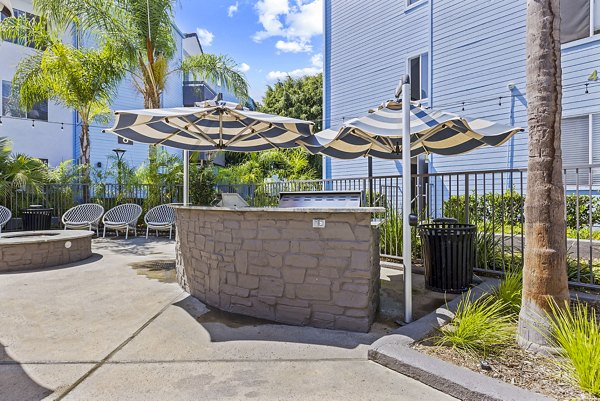 Grill and patio area at Enclave Apartments with modern outdoor seating and lush greenery Perfect for entertaining and relaxation