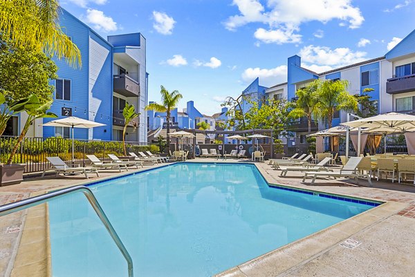 Resort-style pool at Enclave Apartments featuring cabanas and lush landscaping