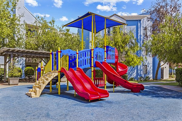 Playground with colorful slides and play structures at Enclave Apartments, ideal for family-friendly living