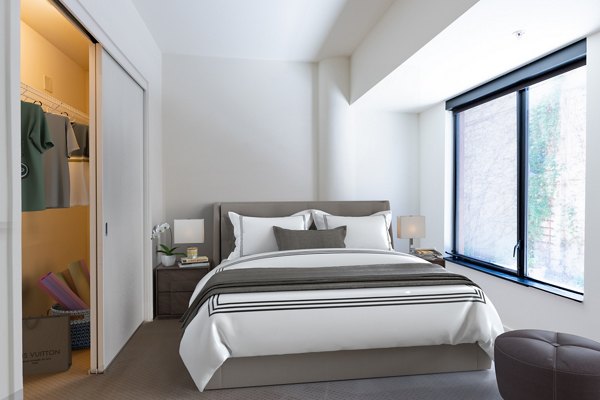 Cozy bedroom featuring contemporary design and natural light at The Dudley Apartments, luxury living offered by Greystar