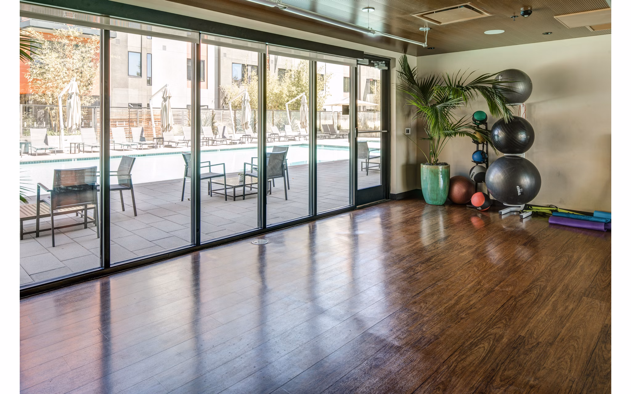 Yoga studio with bamboo floors and mirrored walls at The Dudley Apartments fitness center
