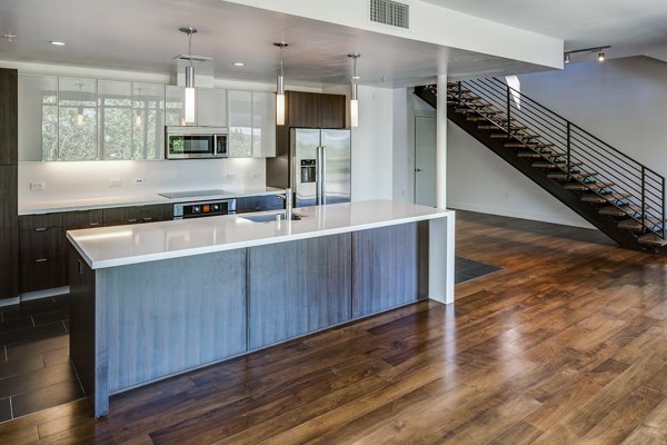 Modern kitchen boasting granite countertops and stainless steel appliances at The Dudley Apartments
