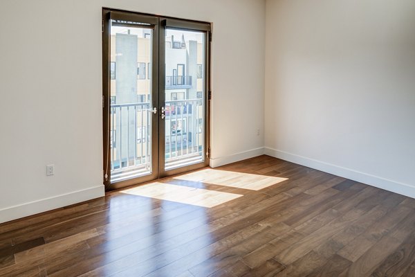 Spacious living room with modern decor and large windows at The Dudley Apartments, luxury community by Greystar