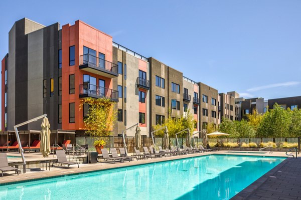 The Dudley Apartments: Resort-style pool with loungers and palm trees, ideal for relaxation and recreation in a luxury setting