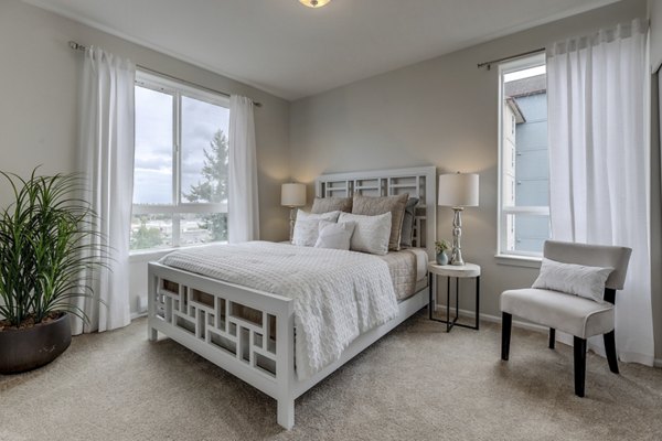 Modern bedroom featuring elegant decor and large windows in Apex Apartments